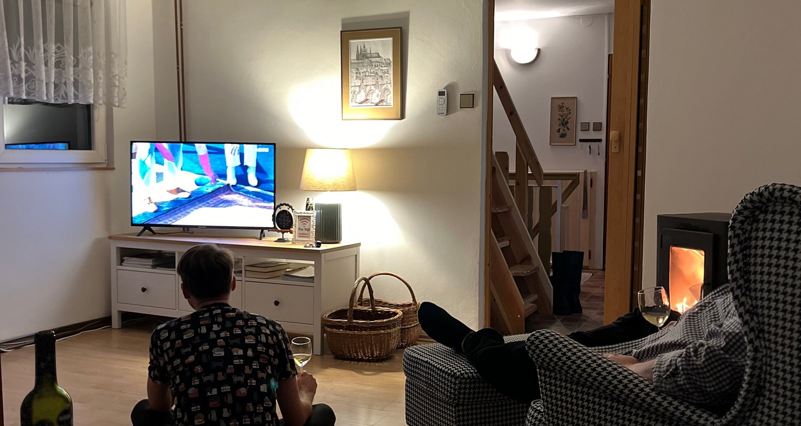 Společenská místnost s rozkládací sedací soupravou, konferenčním stolkem, klimatizací, TV a krbovými kamny.